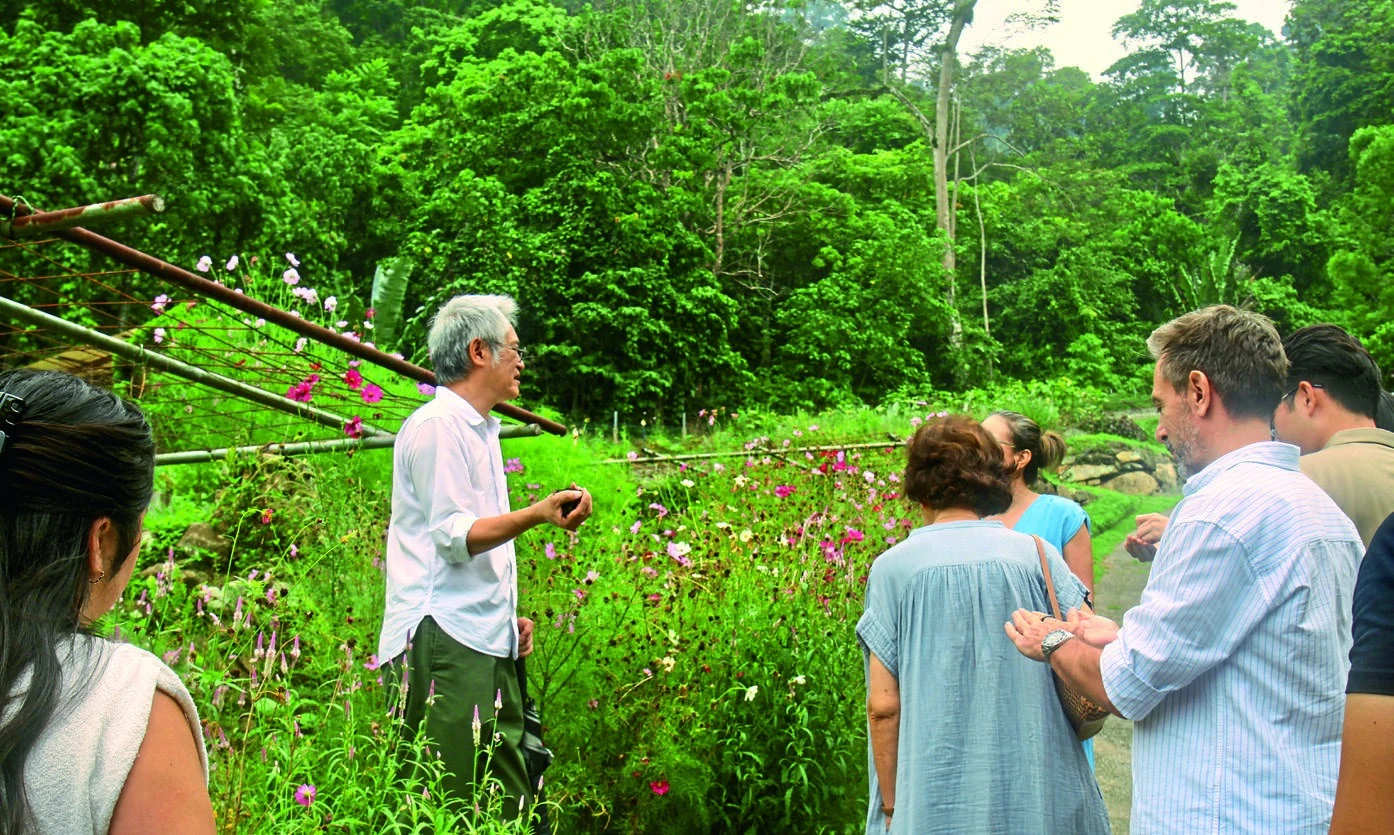 A small group follows their host through the lush gardens at A Little Farm on the Hill