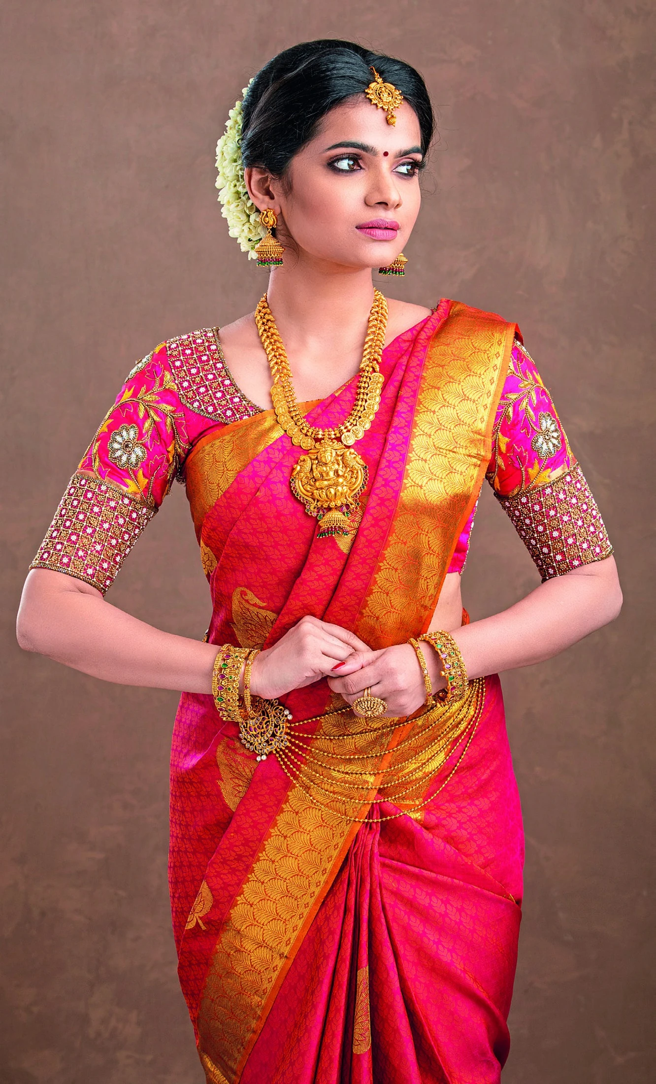 A woman in a red saree with an intricate gold border